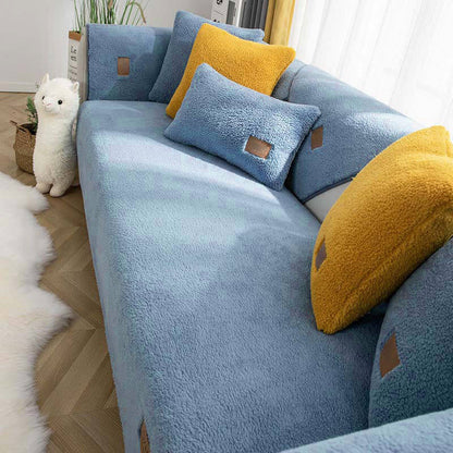 Cat beside a blue sherpa-style sofa cover with yellow cushions